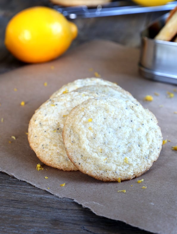 Lemon poppyseed cookies laying on top of each other on brown surface 