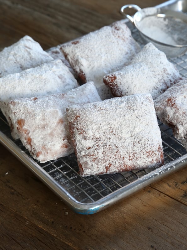 Beignets coated with powdered sugar on metal tray