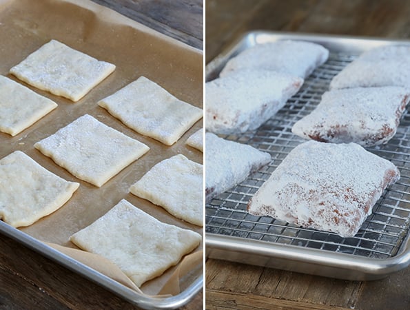 Raw and cooked Beignets coated with powdered sugar on metal tray