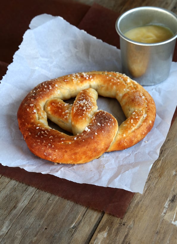 One baked gluten free soft pretzel on white parchment on a table