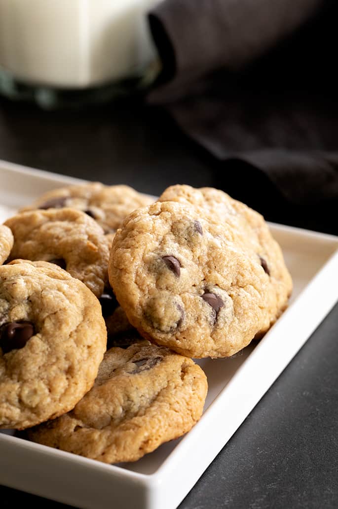 A corner of a white tray with small peanut butter oatmeal chocolate chip cookies on it