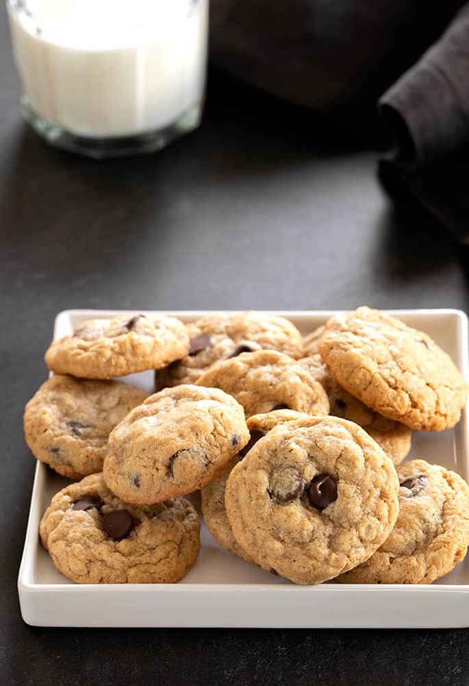 A pile of peanut butter oatmeal chocolate chip cookies on a square white tray