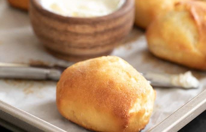 Gluten free Texas roadhouse rolls baked on tray, served with softened butter.