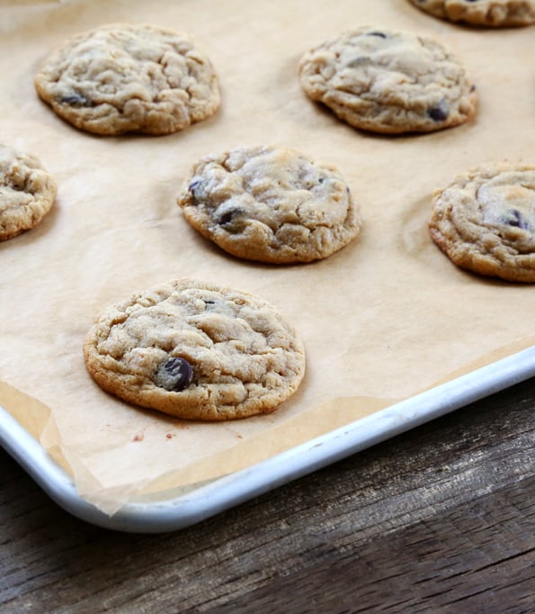 A baking tray with peanut butter oatmeal chocolate chip cookies on a wooden table