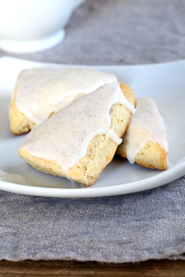 Three small vanilla scones with white icing on a plate