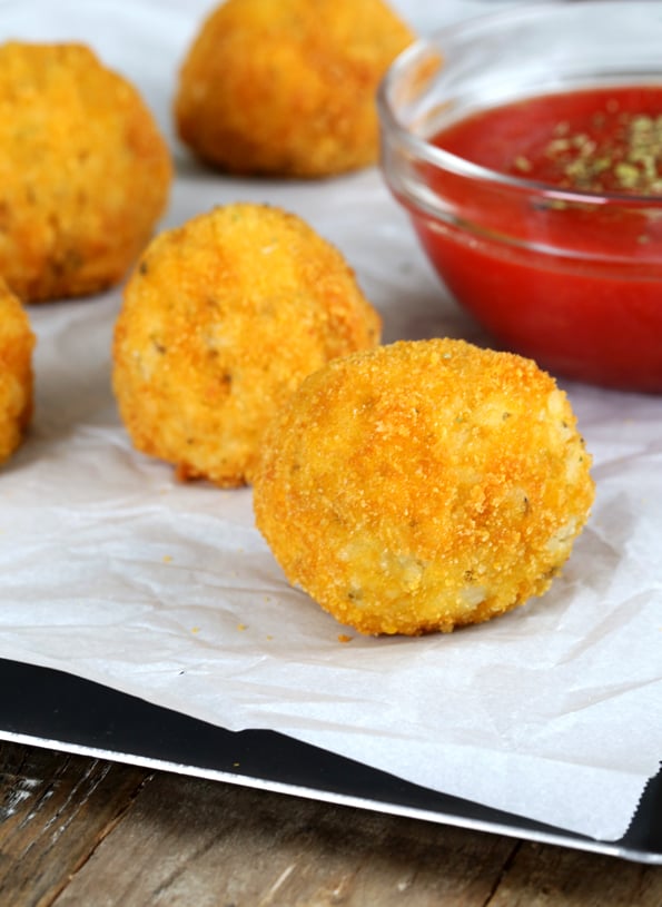 Rice balls on white surface and sauce in back 