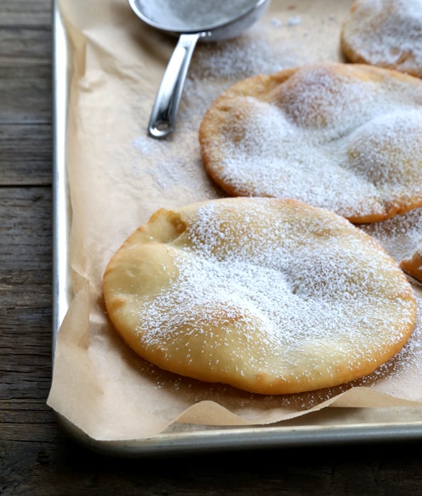 Fry bread with powdered sugar on metal tray