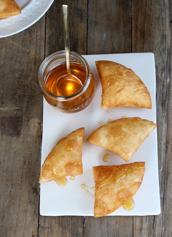 Overhead view of Sopapillas on white plate with honey drizzle 