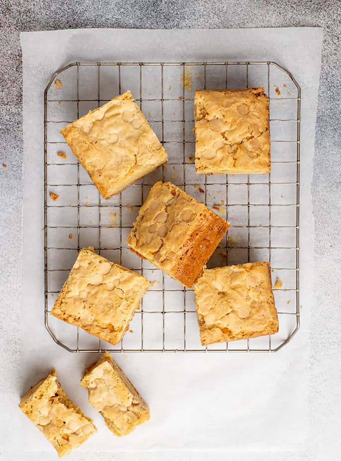 Overhead image of cut blondies on a wire rack with one broken in half