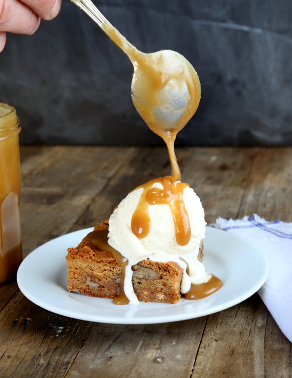 Maple Butter gluten free Blondies with ice cream and Carmel drizzle on a white plate 