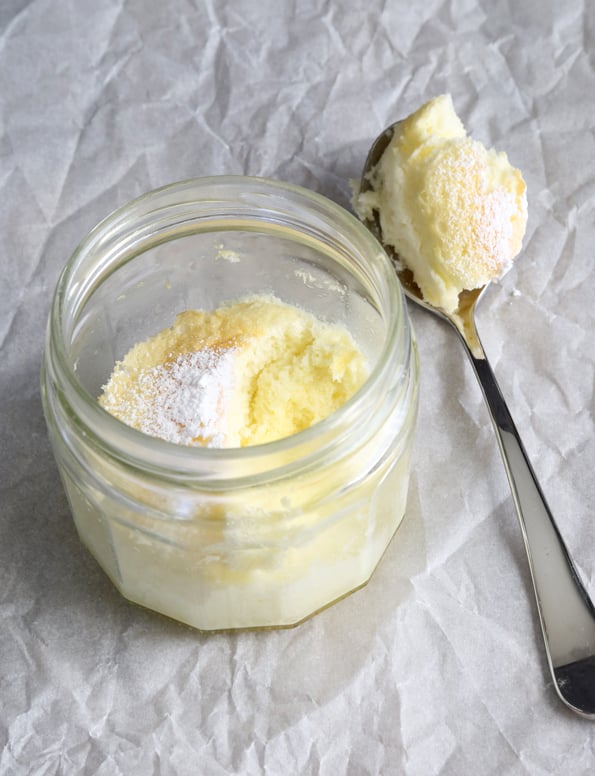 Yellow cake in a jar and on a spoon, both on white paper