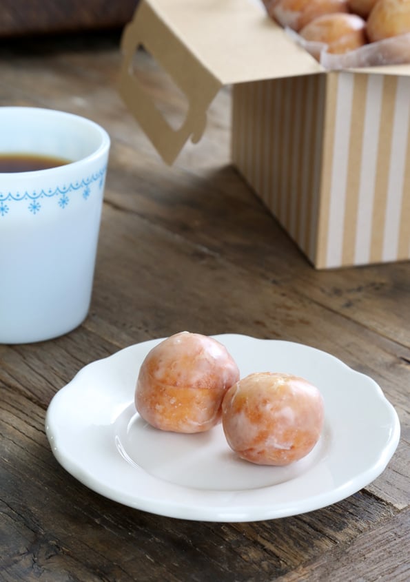 A plate of donut holes and a cup of coffee.