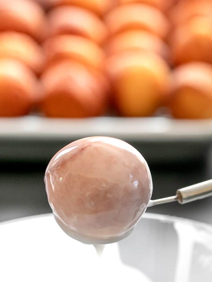 Donut holes being dipped in glaze