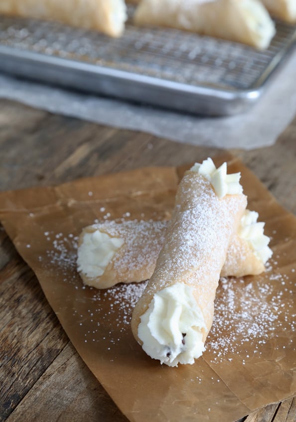 2 cannolis on a brown surface 