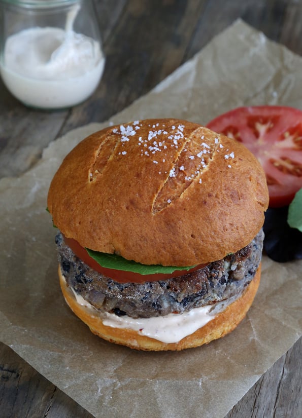 A close up of a black bean burger on a pretzel bun