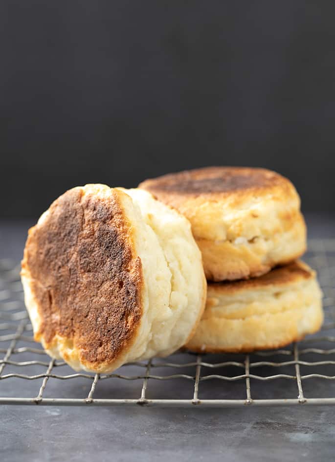 Stack of 2 English muffins with one more on its side all on a wire rack