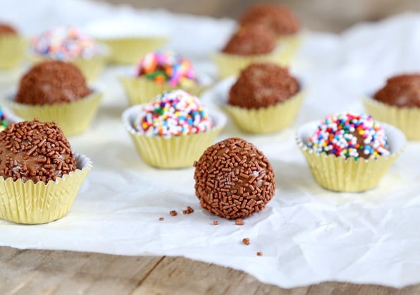 A close up of a Brigadeiro with chocolate sparkles on a white surface 