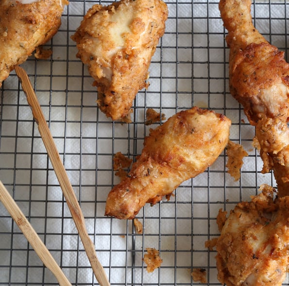 Overhead view of gluten free fried chicken on wire rack with tongs