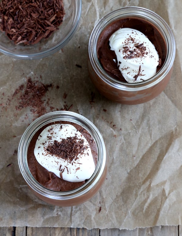 Nutella mousse with hip cream on top in jars on brown surface 