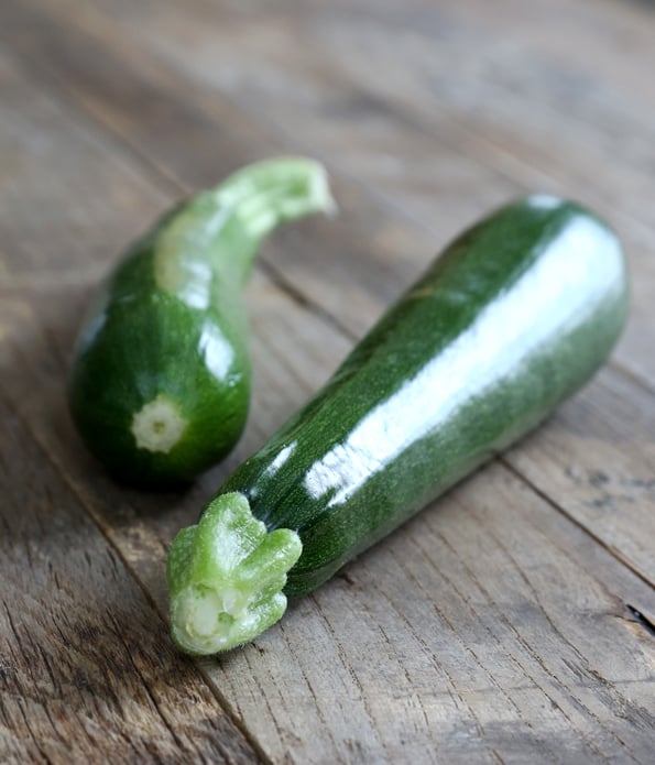 2 zucchinis on a wooden surface 