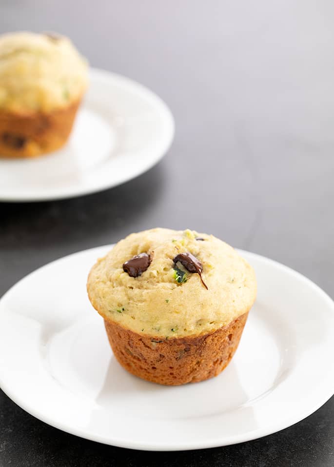 Two zucchini muffins each on a small white plate