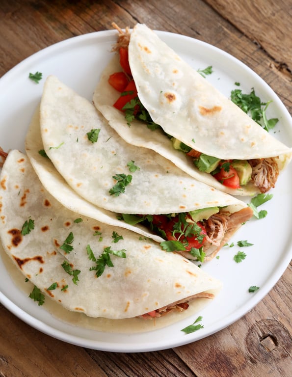 Overhead view of 3 carnitas on a white plate