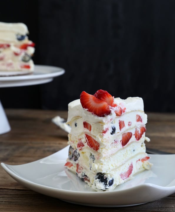 A piece of crepe cake with a strawberry on top on white plate