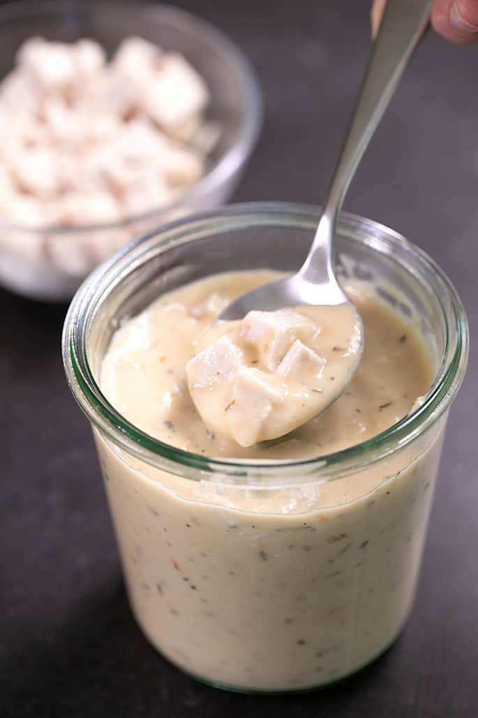 Fingers holding spoon with closeup on spoonful of cream of chicken soup