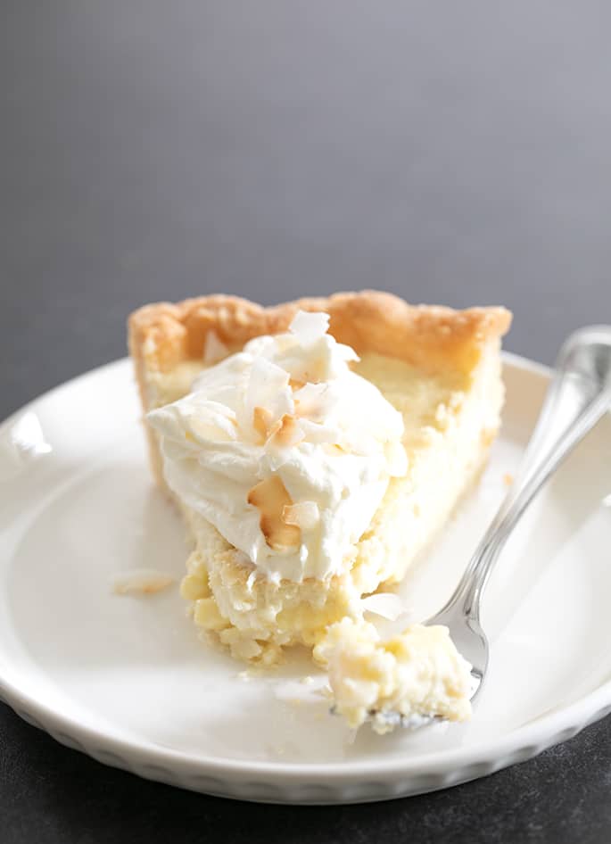 Coconut cream pie slice on plate with forkful