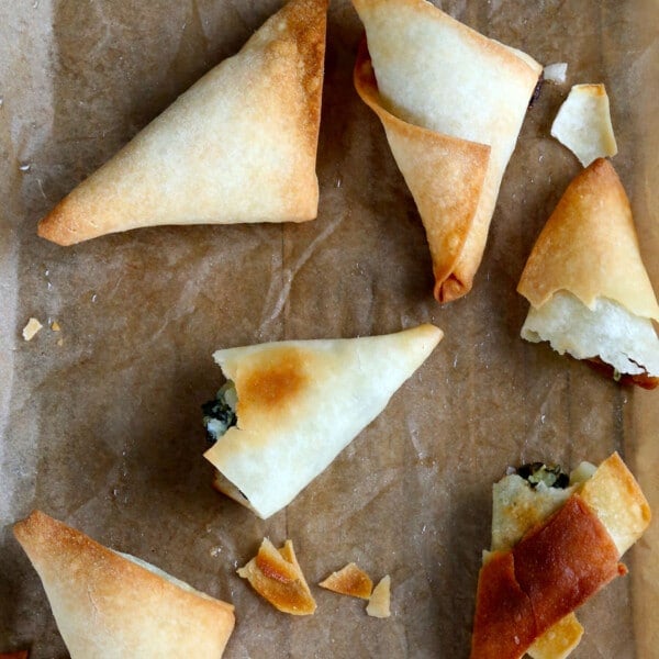 gluten free phyllo dough made into triangular shaped filled with green spinach on brown paper