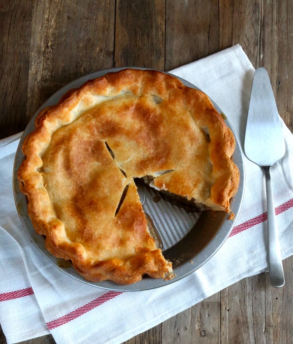 Overhead image of a double crust pie with a piece taken