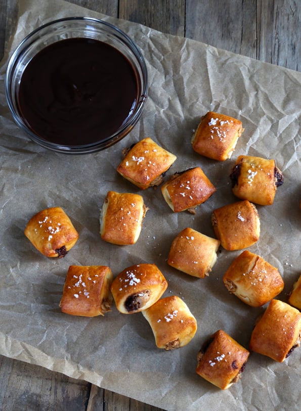 Overhead view of pretzel bites and a bowl of chocolate sauce on brown surface 