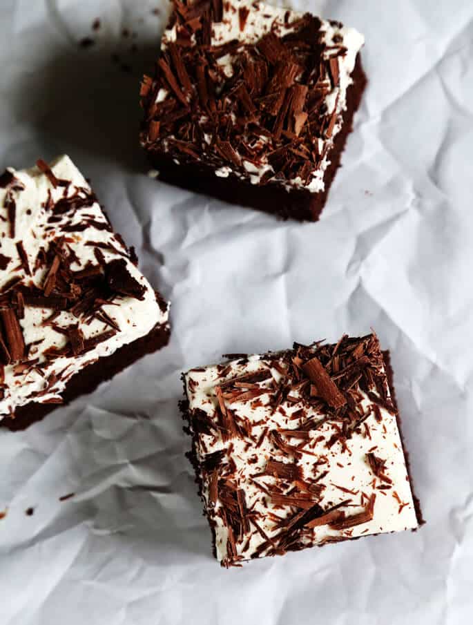 An overhead view of chocolate poke cake on a white surface 