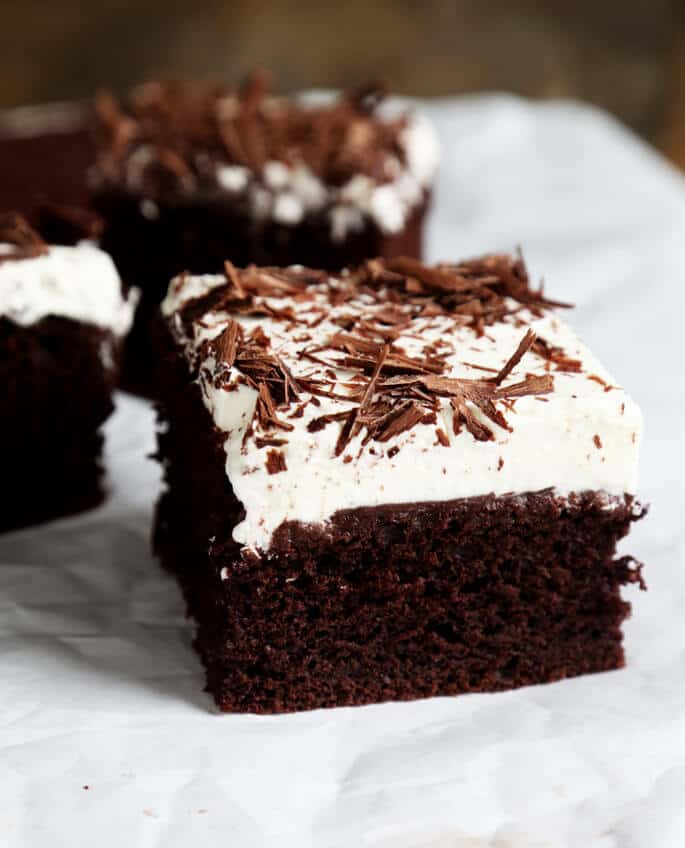 A close up of a piece of chocolate poke cake on a white surface 