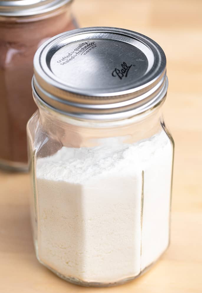 White hot chocolate powder in glass jar with metal lid