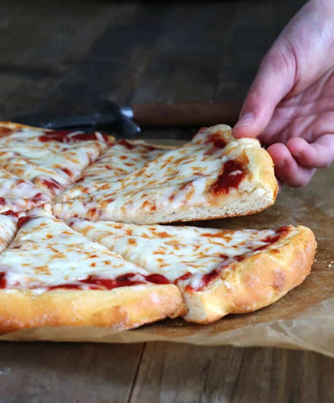 A close up of person taking a slice of pizza from pizza pie 