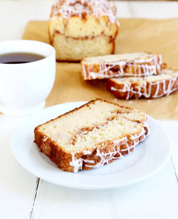 Cinnamon swirl bread on a white plate with a cup of coffee in back