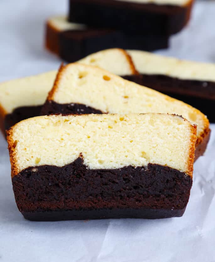 A close up of a slice pf brownie butter cake on white surface