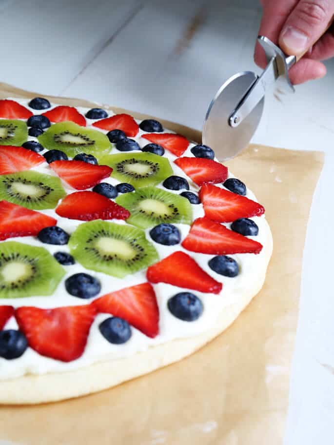 Side view of a fruit pizza being cut