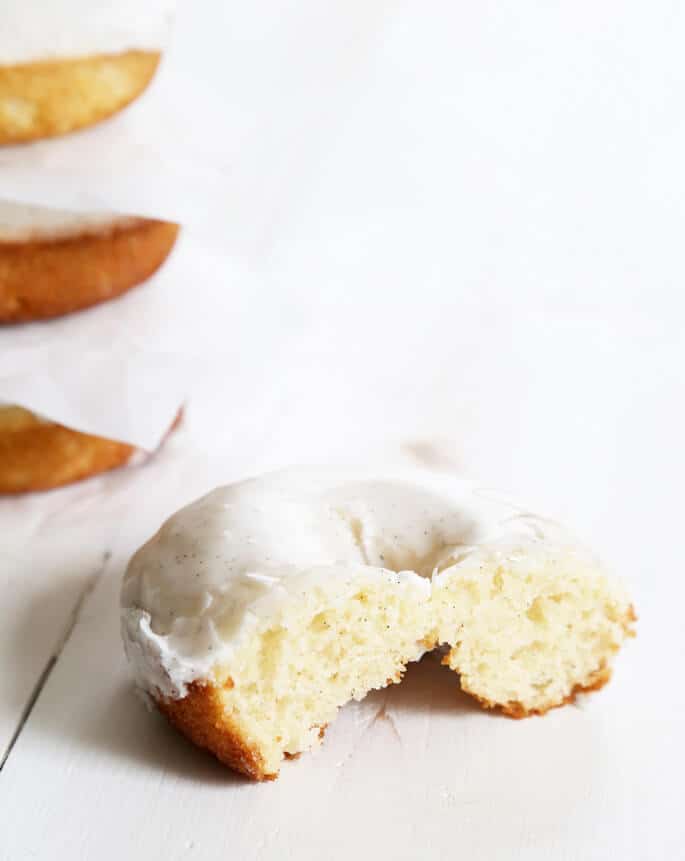 A half eaten vanilla cake donut with white glaze