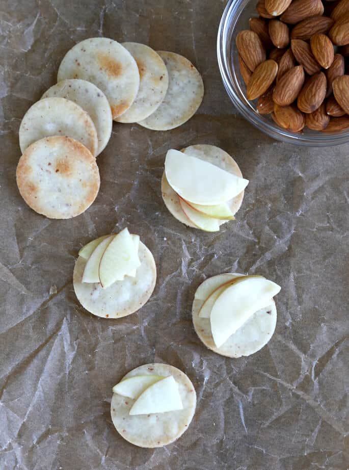 Overhead view of row of crackers and crackers with cheese on brown surface