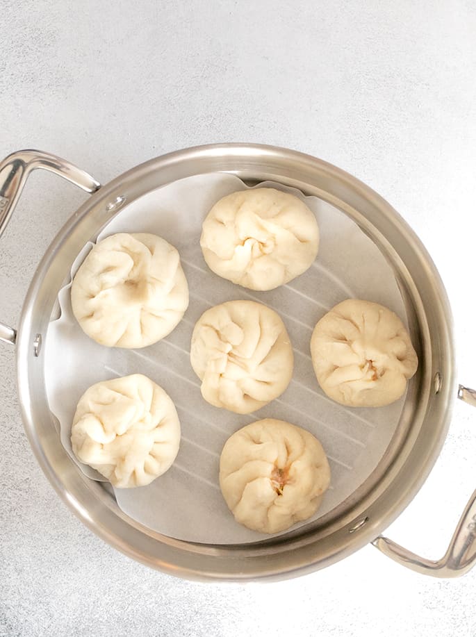 raw shaped Chinese meat buns in a steamer