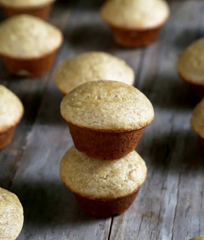 A wooden cutting board, with a stack of gluten free mini banana muffins