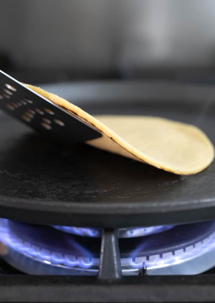 Lifting a corn tortilla from a skillet with a spatula