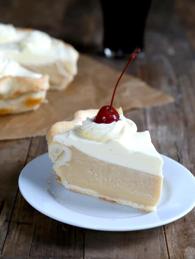 A close up of a slice of root beer pie with cherry on top on white plate 