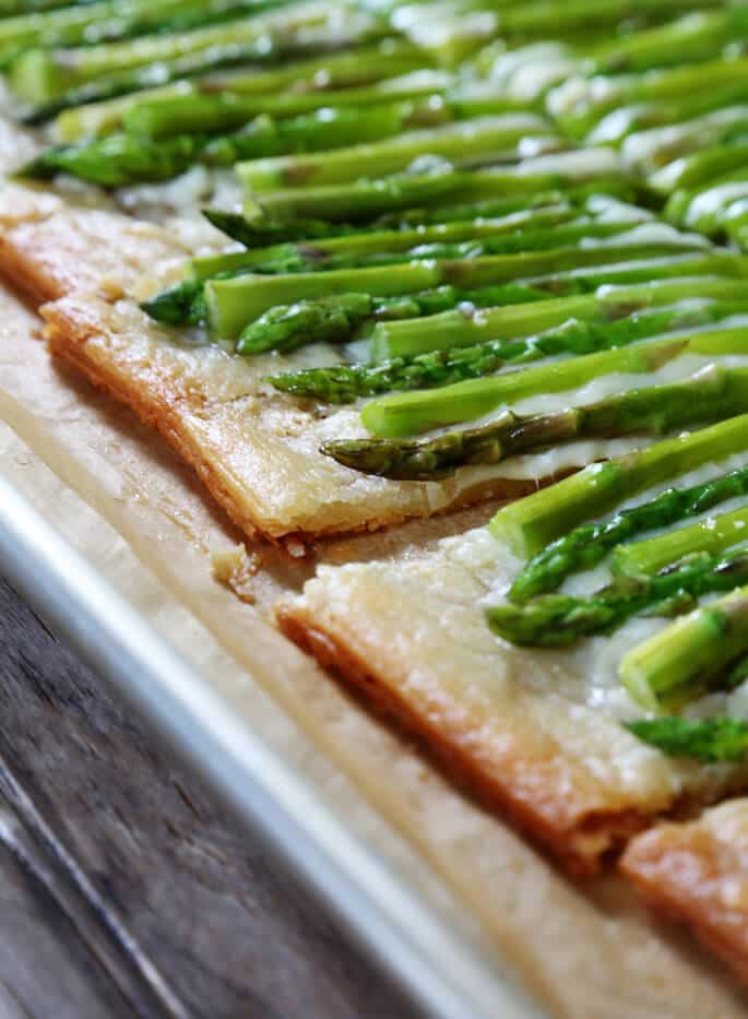 A close up of slices of asparagus tarts on metal tray