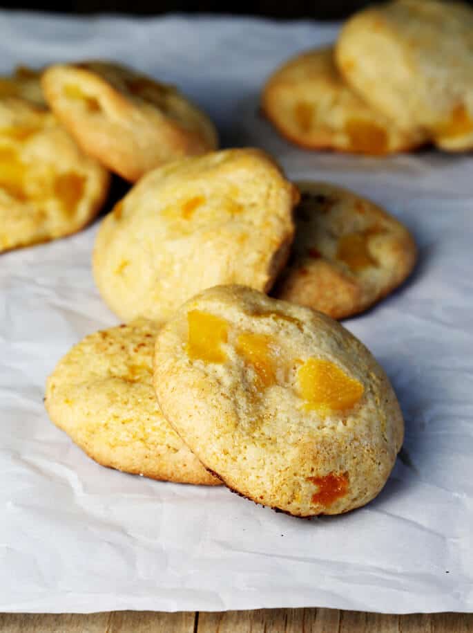 Peach pie cookies laying on side of each other on white surface 