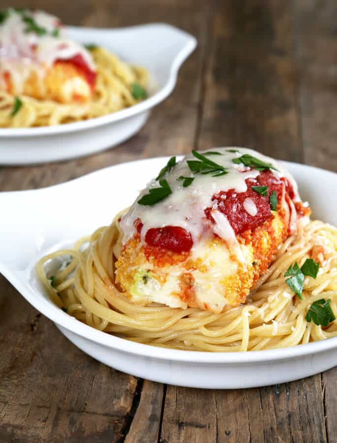 Spaghetti and zucchini chicken parmesan on a white plate