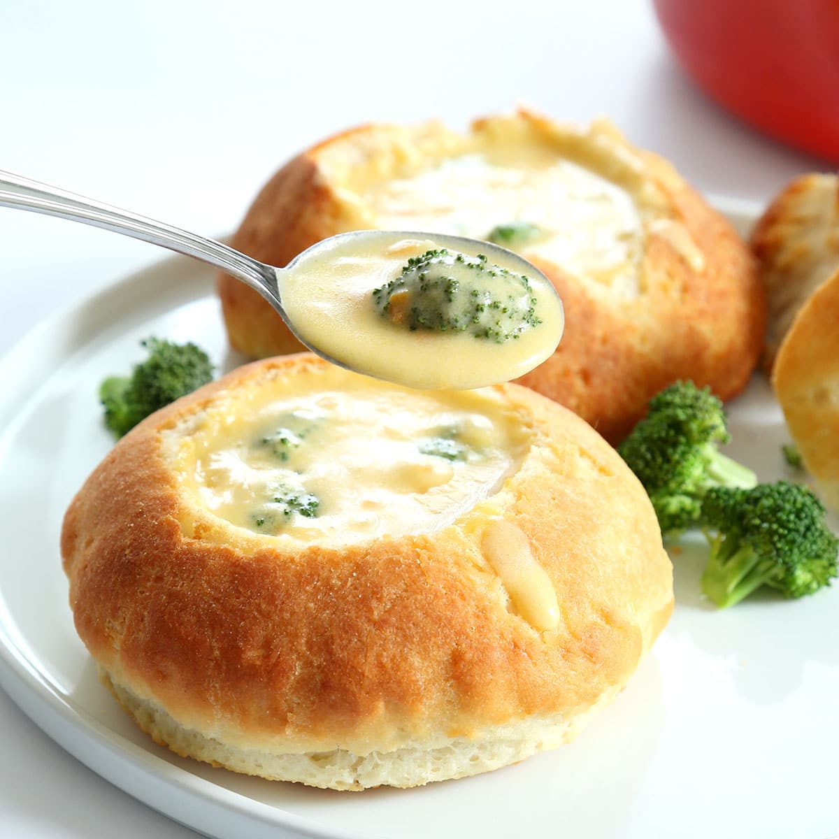 spoon holding gluten free broccoli cheddar soup from bread bowl