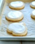 A close up of a pumpkin cutout sugar cookie on parchment paper